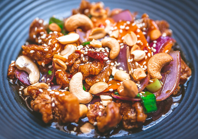 restované asijské kuřecí Gong Bao s rýží na tmavém talíři